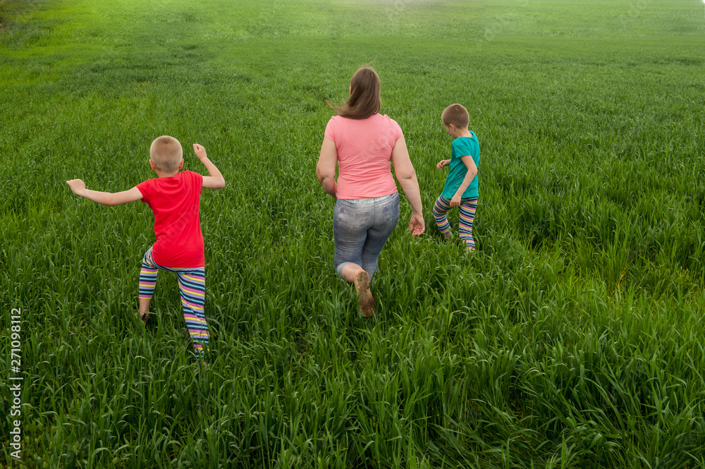 Happy mother with children playing on a green field with wheat..Unity with nature concept Happy mother with children playing on a green field with wheat..Unity with nature concept