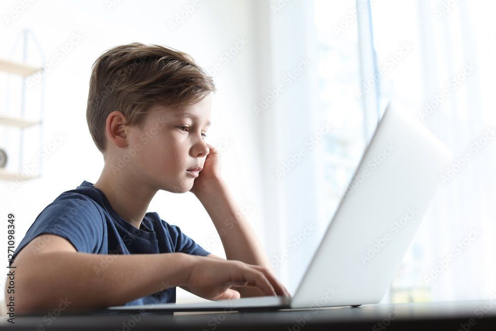 Little child with laptop at table indoors. Danger of internet Little child with laptop at table indoors. Danger of internet