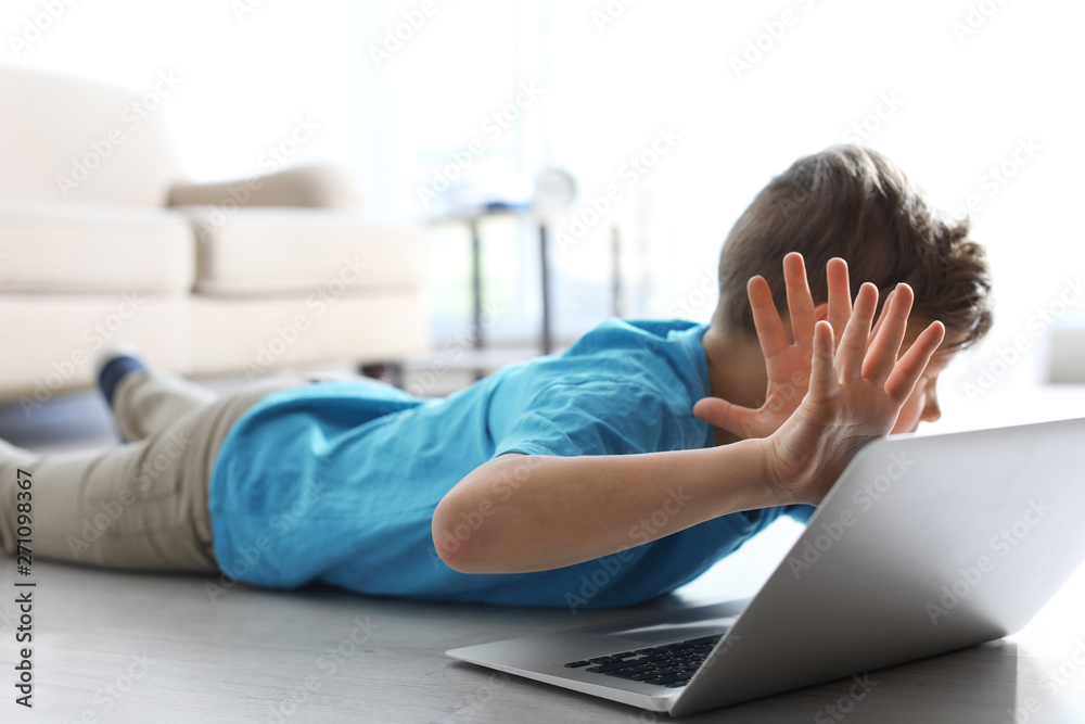 Fototapeta premium Frightened little child with laptop on floor indoors. Danger of internet