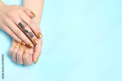 Woman showing manicured hands with golden nail polish on color background, top view. Space for text