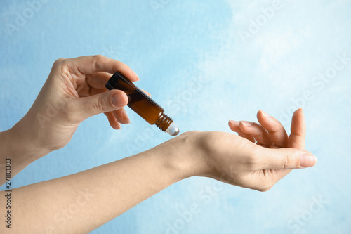 Obraz na plátne Woman applying essential oil on her wrist against color background, closeup