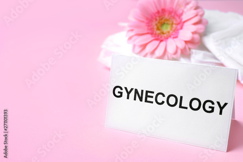 Card with word Gynecology, packed menstrual pads and flower on color background. Space for text
