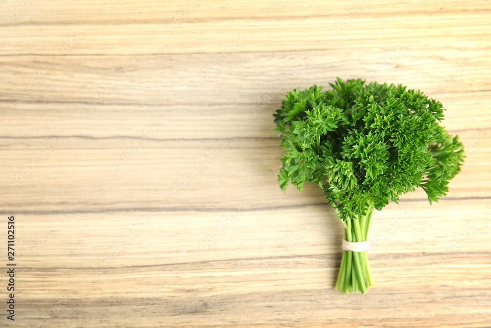 Bunch of fresh green parsley on wooden background, top view. Space for text Bunch of fresh green parsley on wooden background, top view. Space for text