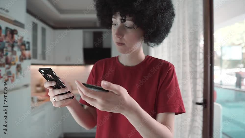 Mobile payment, shopping concept. Afro haired characteristic young girl buy something on smartphone with credit card Mobile payment, shopping concept. Afro haired characteristic young girl buy something on smartphone with credit card