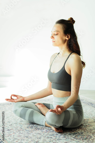 Young attractive smiling woman practicing yoga in a bright room photo