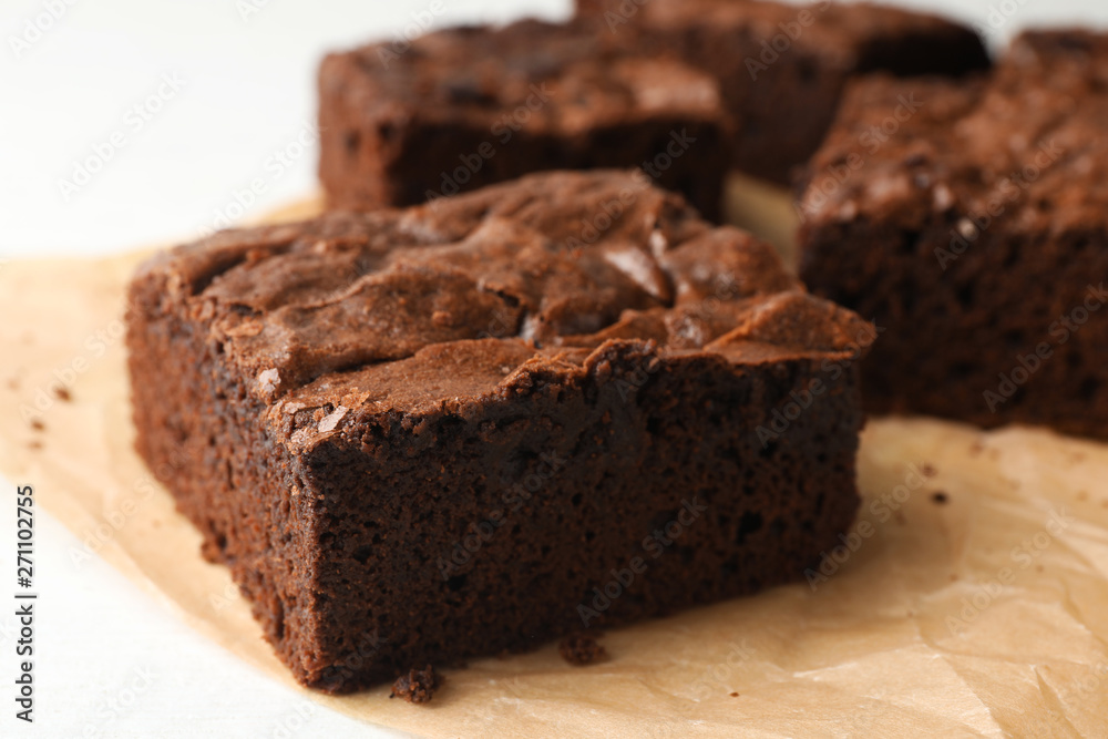 Parchment paper with fresh brownies on white table, closeup. Delicious chocolate pie Parchment paper with fresh brownies on white table, closeup. Delicious chocolate pie