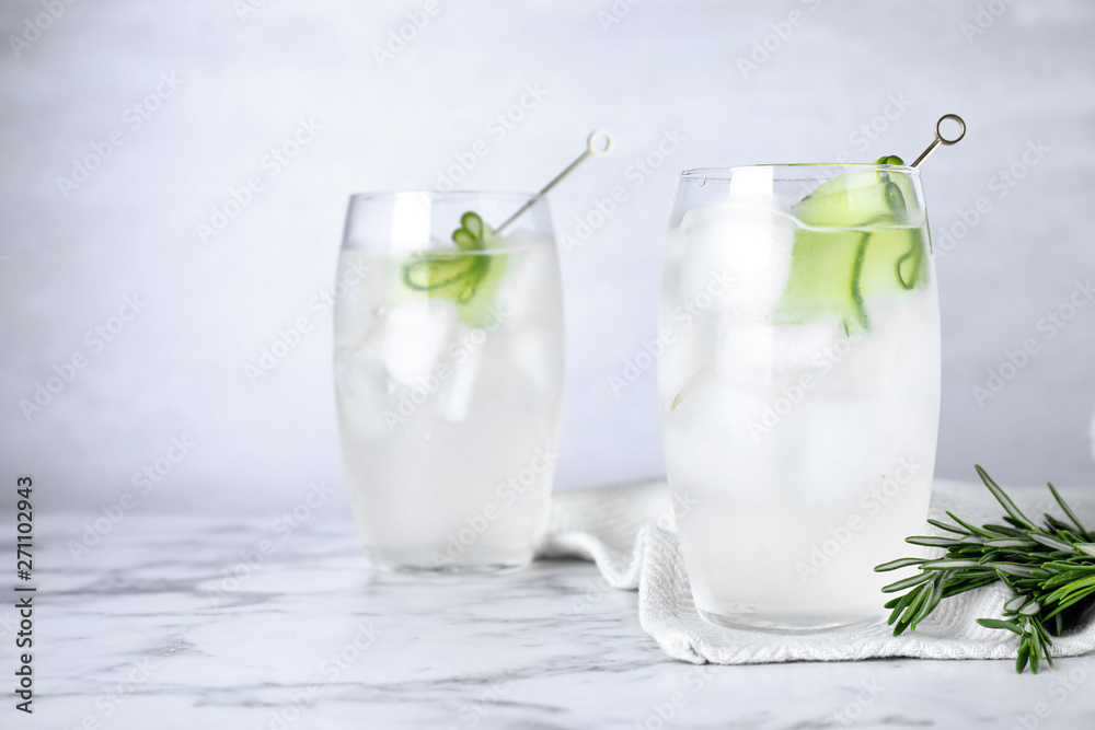 Glasses of martini with cucumber on marble table against light background. Space for text Glasses of martini with cucumber on marble table against light background. Space for text
