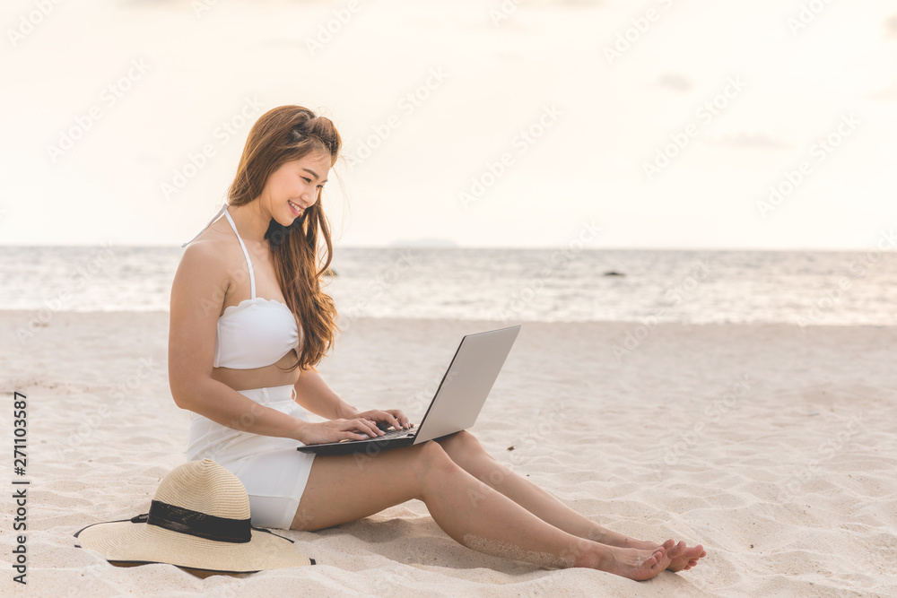 Cute Asian woman working with computer laptop on the tropical island beach with sunset feeling so happiness and comfortable,Summer Vacations and Freelance concept