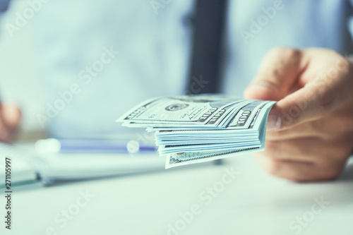 Man giving money us dollar banknotes and holding cash in hands. Money credit concept. Toned picture.