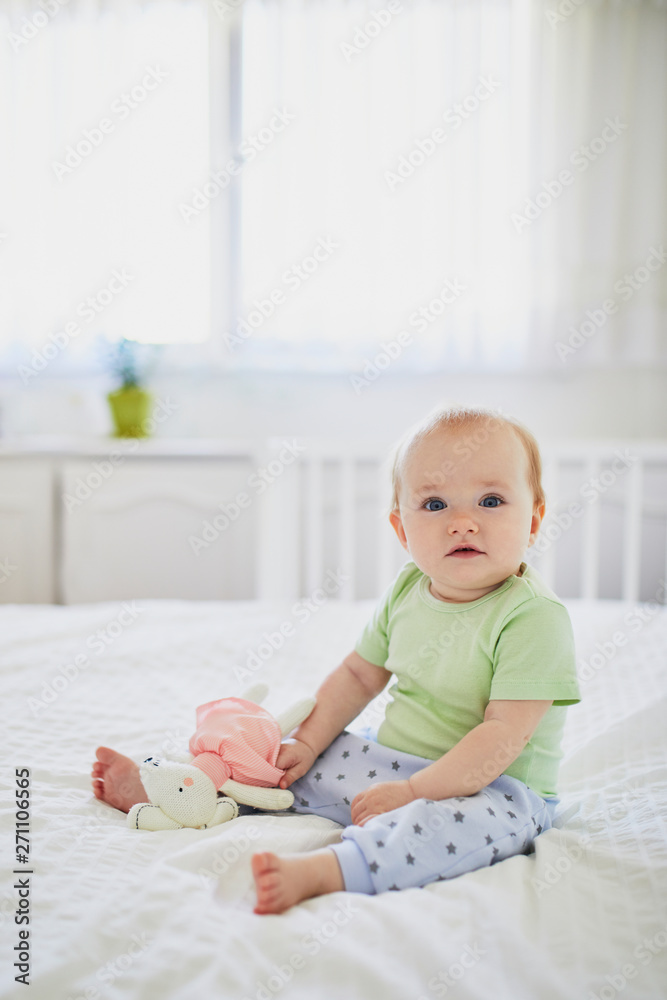 Baby girl sitting on bed and laughing Baby girl sitting on bed and laughing