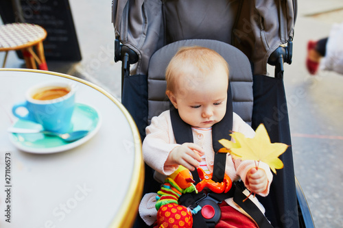 baby girl in pushchair in Parisian outdoor cafe