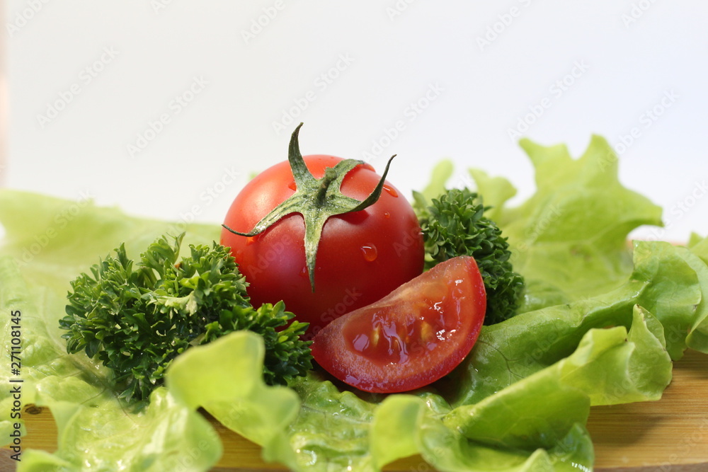 Red tomatoes with greenery on the wooden board Red tomatoes with greenery on the wooden board