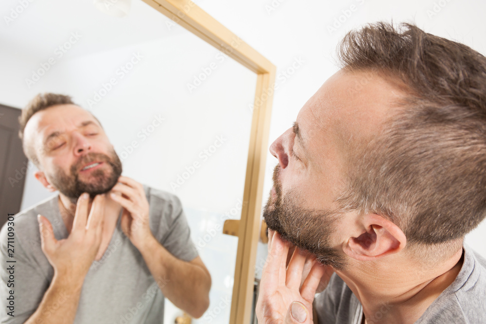 Obraz premium Man looking at beard in mirror