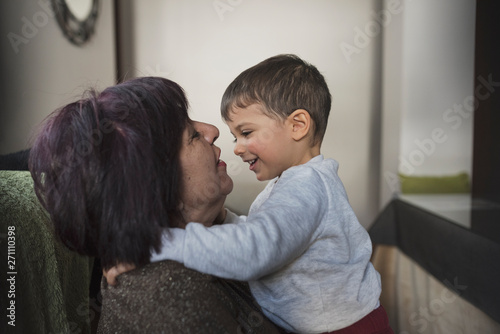 Grandmother and grandson indoors image. Hug in living room. photo
