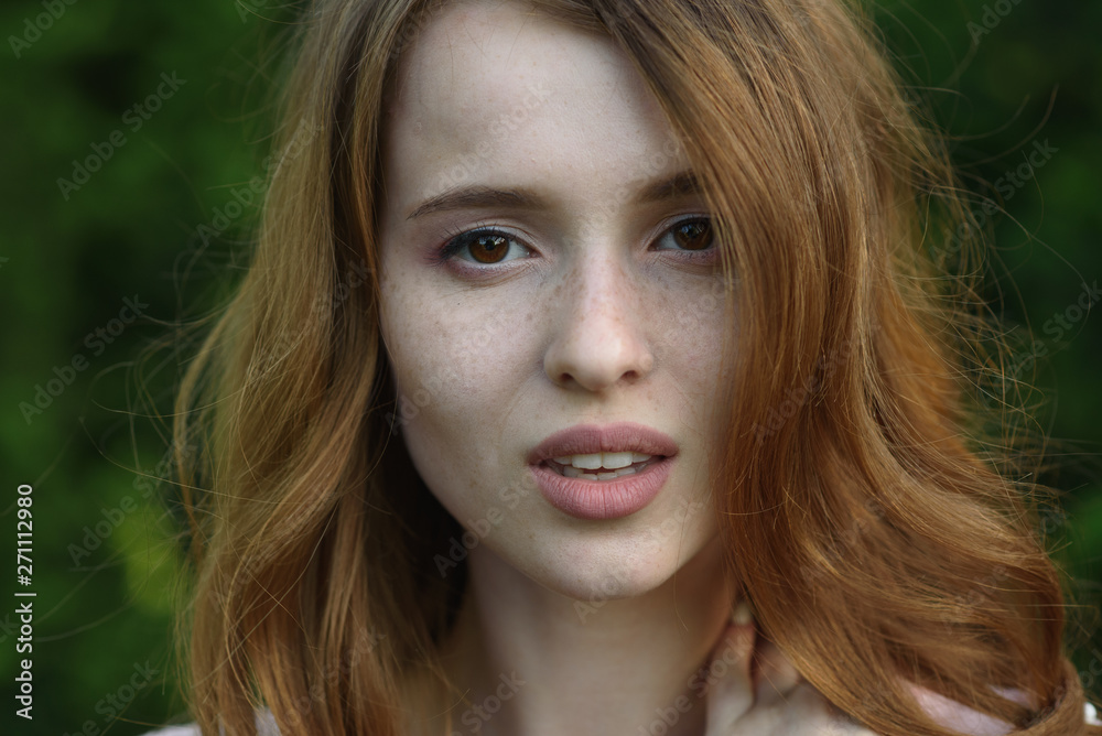 Fototapeta premium Beautiful and happy young girl walks in the park and enjoys life