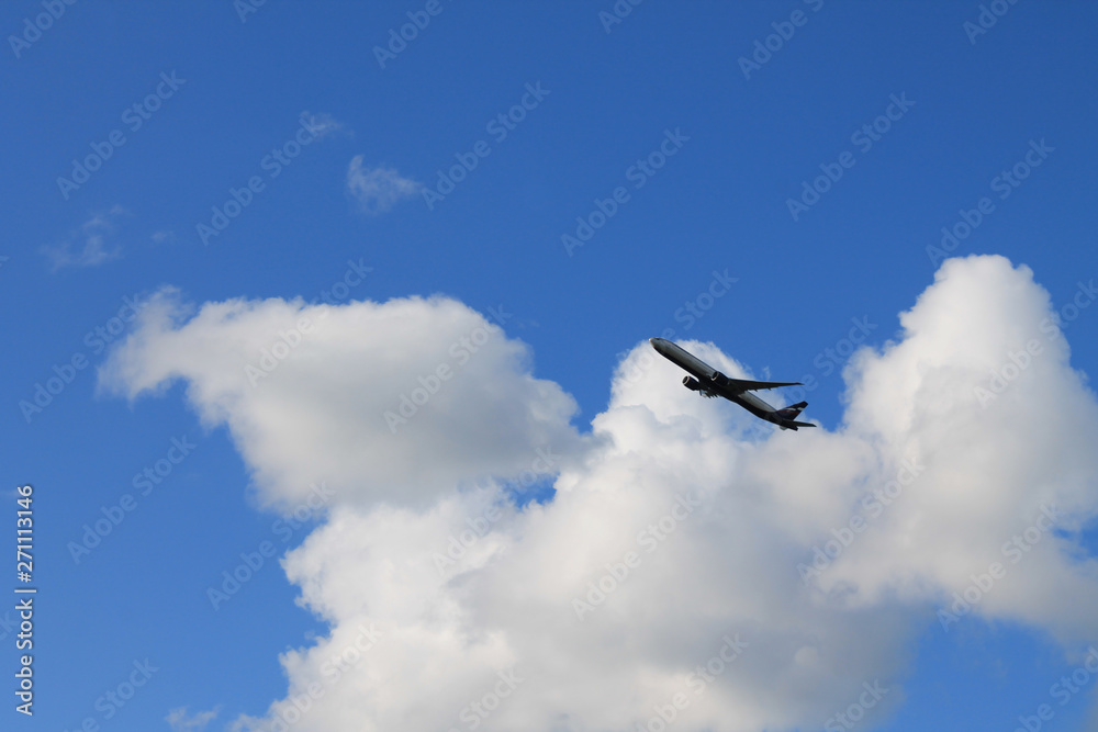 Fototapeta premium Flying plane in the blue sky with clouds