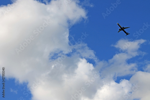 Flying plane in the blue sky with clouds