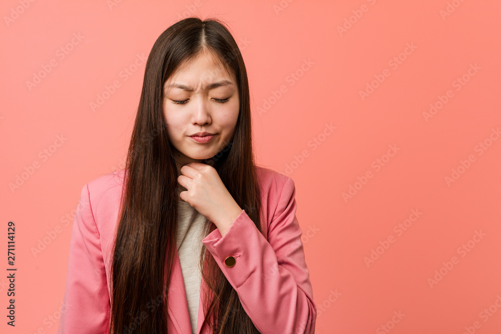 Young business chinese woman wearing pink suit suffers pain in throat due a virus or infection. Young business chinese woman wearing pink suit suffers pain in throat due a virus or infection.