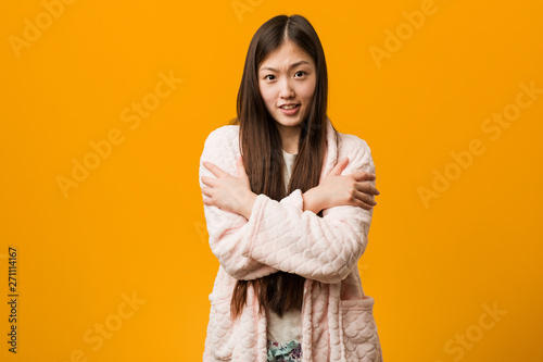 Young chinese woman in pajama going cold due to low temperature or a sickness. © Asier
