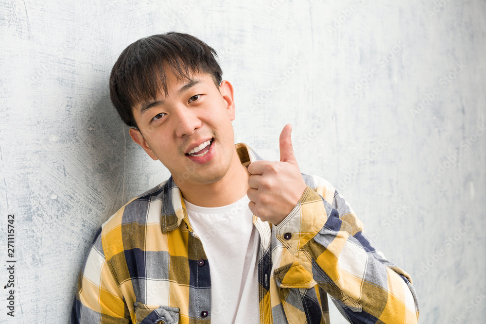 Young chinese man face closeup smiling and raising thumb up Young chinese man face closeup smiling and raising thumb up