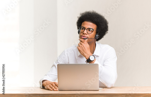Young telemarketer black man doubting and confused