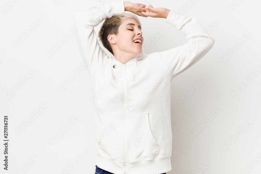 Young curvy woman wearing a white hoodie stretching arms, relaxed position. Young curvy woman wearing a white hoodie stretching arms, relaxed position.