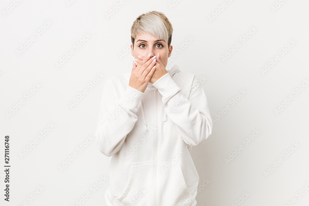 Young curvy woman wearing a white hoodie shocked covering mouth with hands. Young curvy woman wearing a white hoodie shocked covering mouth with hands.