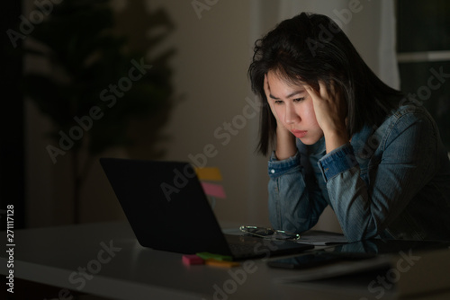 Foto Candid of young asian single female student work late night stress out with project research problem on computer laptop or notebook at home office