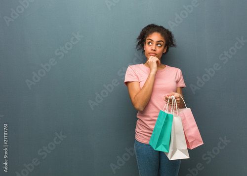 Young black woman thinking about an idea. She is holding a shopping bags. © Asier