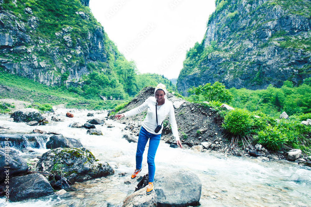 young smiling woman posing happy at mountain river on the rock, lifestyle people on vacation concept 