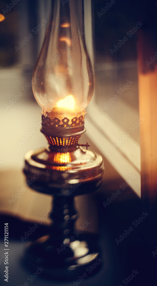 Vintage kerosene lamp stands on a white windowsill