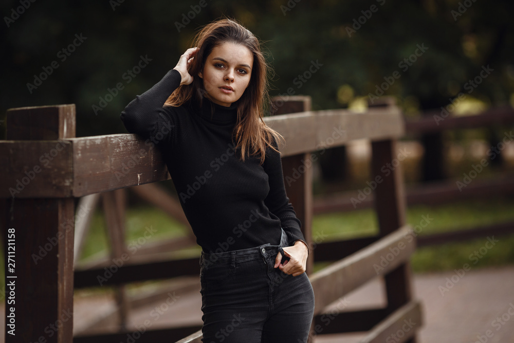 A beautiful young brunette walks through the autumn park in a black sweater and coat, A beautiful young brunette walks through the autumn park in a black sweater and coat,