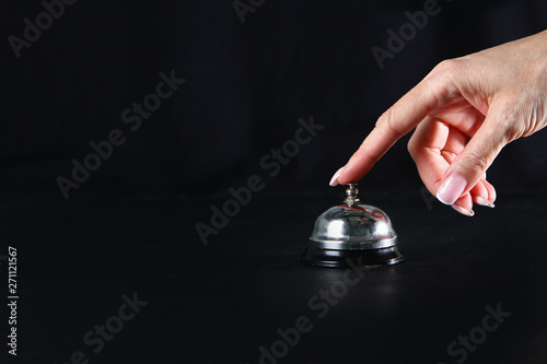 Female hand presses the call button staff call. Restaurant business or bar. Copy space. Photo on a black background. Visitor service concept. photo