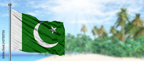 Fotografi Waving Pakistan flag in the sunny blue sky with summer beach background