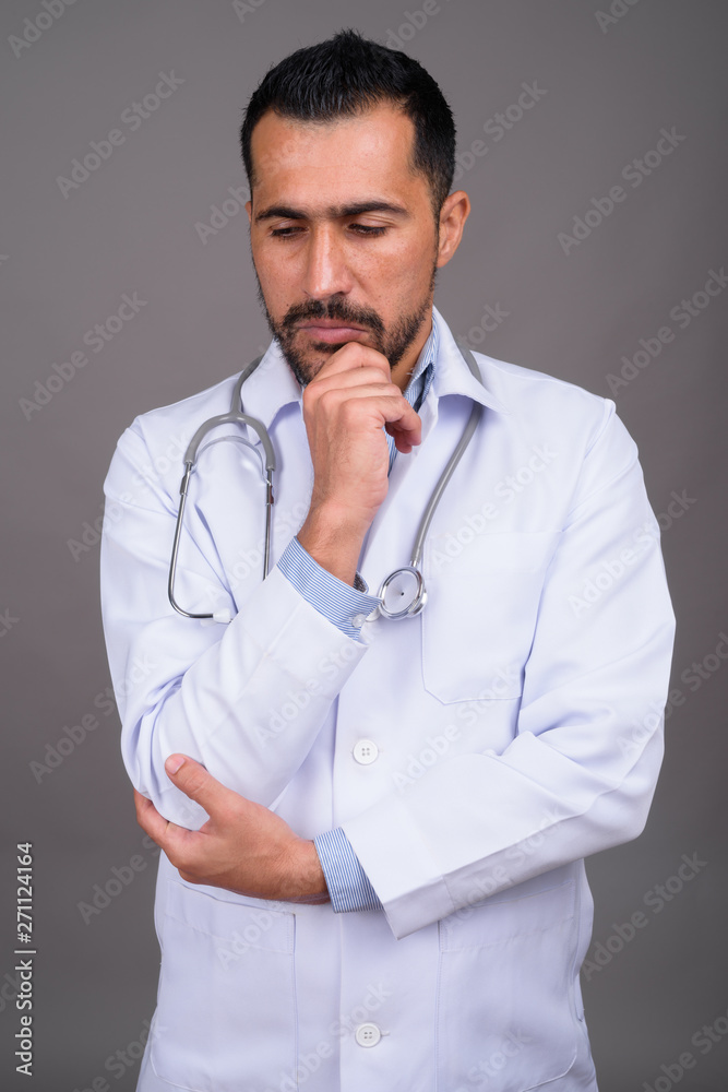 Handsome bearded Persian man doctor against gray background Handsome bearded Persian man doctor against gray background