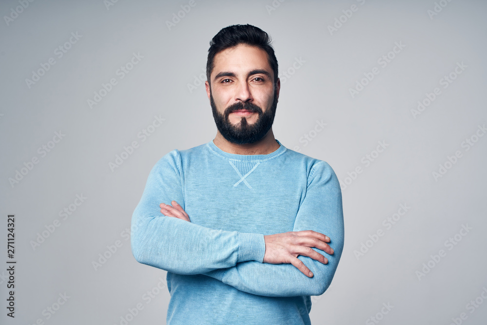 Confident Hispanic man in blue pullover standing with folded hands Confident Hispanic man in blue pullover standing with folded hands