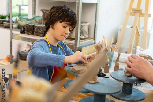 Schoolboy feeling involved in sculpting clay animals photo