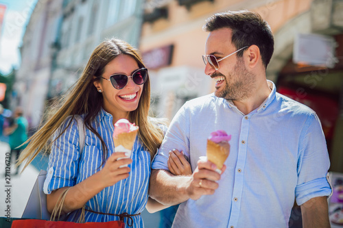 Happy couple having date and eating ice cream after shopping