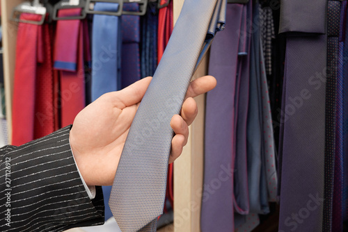 Close up of male hand holding, showing grey necktie.