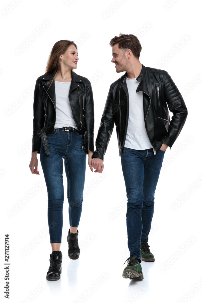 Positive couple walking and holding hands while smiling Positive couple walking and holding hands while smiling