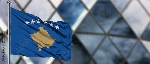 Фотография Kosovo flag waving in the wind against blurred modern building