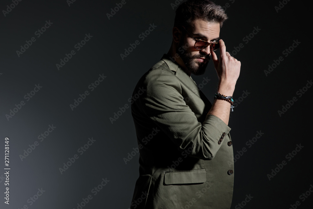 Side view of mysterious young man arranging his sunglasses Side view of mysterious young man arranging his sunglasses