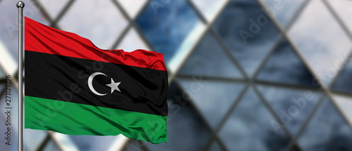 Bild auf Leinwand Libya flag waving in the wind against blurred modern building