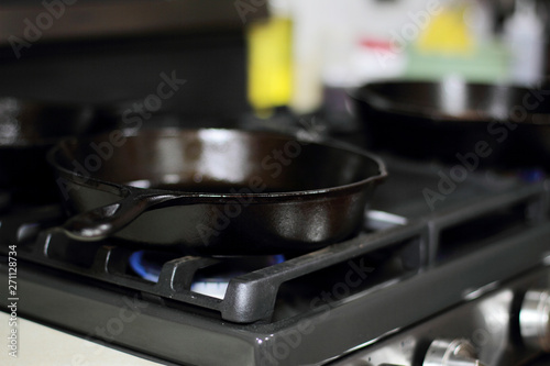 Cast iron skillets heating up on a natural gas stove.
