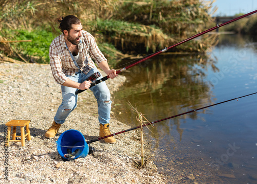 Happy fisherman pulls fish out of the river photo