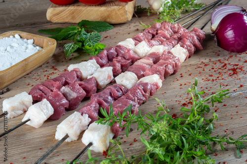 Fotografie uncooked (raw) meat and Turnspit skewing kebap or kebab on metal skewer in the kebab restaurant