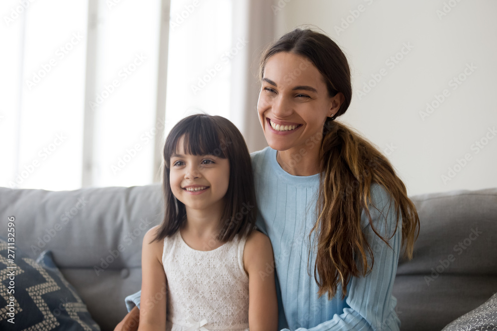 Smiling mom with cute little daughter sit on couch talking Smiling mom with cute little daughter sit on couch talking
