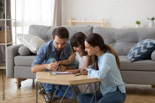 Young parents relax painting together with small daughter