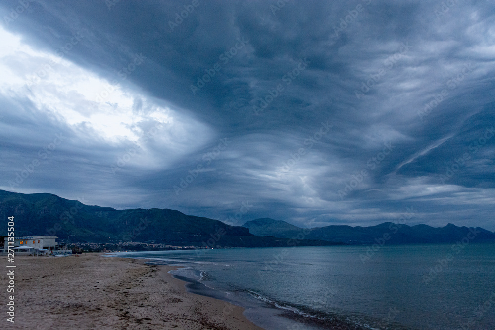 Scenic gray-blue clouds during sunrise over coastline with sandy beach and clear sea water in Alcamo Marina, small town in Sicily, Italy, summer vacation destination Scenic gray-blue clouds during sunrise over coastline with sandy beach and clear sea water in Alcamo Marina, small town in Sicily, Italy, summer vacation destination