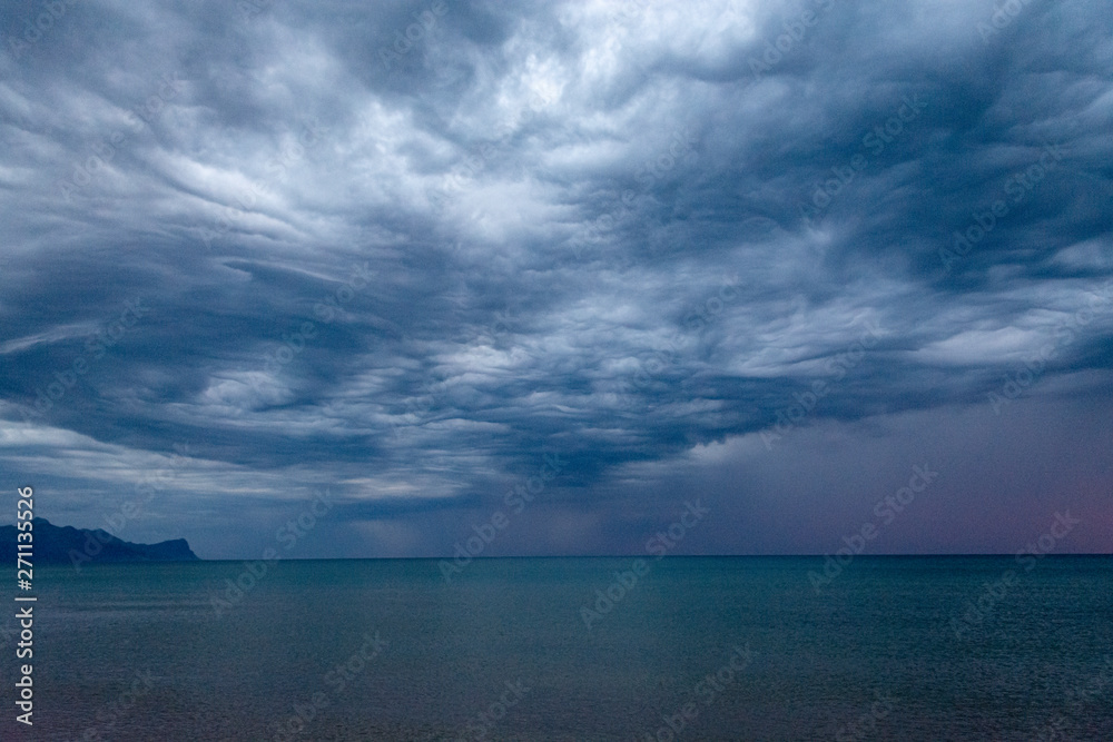 Scenic gray-blue clouds during sunrise over coastline with sandy beach and clear sea water in Alcamo Marina, small town in Sicily, Italy, summer vacation destination Scenic gray-blue clouds during sunrise over coastline with sandy beach and clear sea water in Alcamo Marina, small town in Sicily, Italy, summer vacation destination